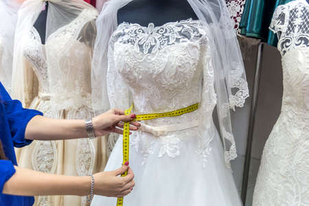 Female hands with measuring tape and wedding dressの写真素材