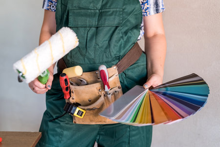 Woman in protective uniform showing painting toolsの写真素材