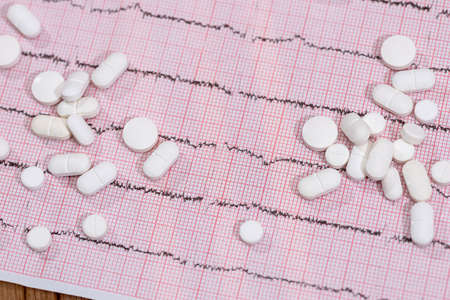 White tablets dispersed on cardiogram close upの写真素材