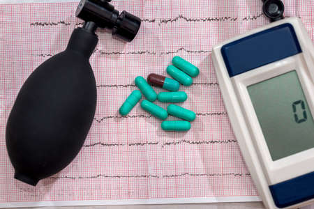 Pills on cardiogram with electronic tonometer, closeupの写真素材
