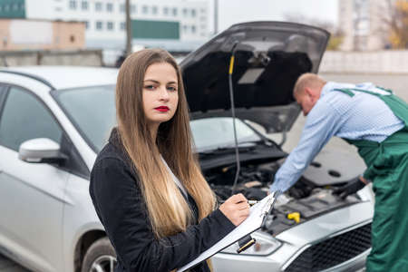 Woman making some notes while worker making diagnostic