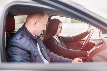 Young woman with instructor sitting in carの写真素材