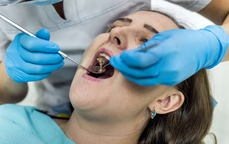 Dentist checking patient's teeth with mirror in dentistryの写真素材