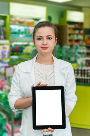 Attractive woman pharmacist showing tablet screen in drugstoreの写真素材