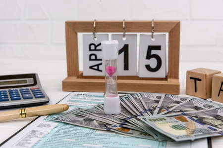 1040 form with wooden calendar, dollar and calculatorの写真素材