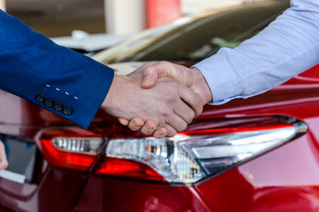 Strong handshakes on car background. Car buy deal