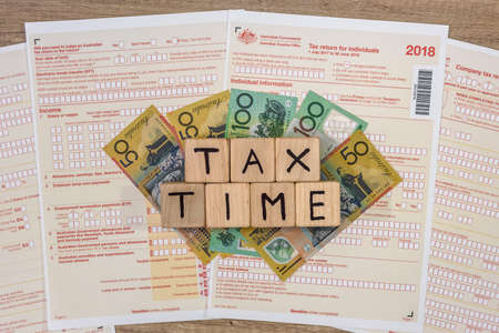 Australian dollar banknotes with wooden cubes at tax form