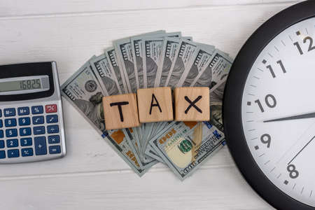 Tax concept with clock, dollar banknotes and cubesの写真素材