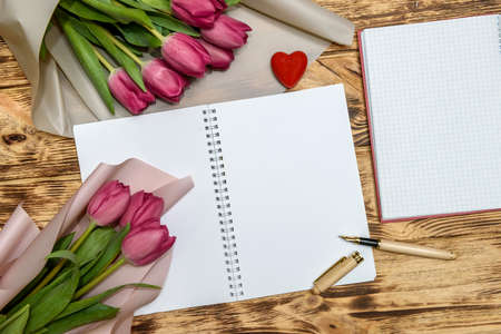 Bouquet of tulips and blank notepad on wooden table