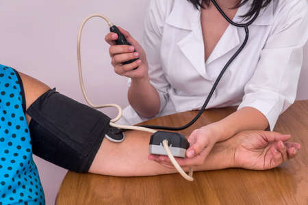 Doctor's and patient's hands with tonometer measuring blood pressure