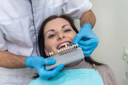 Doctor compare woman teeth with sampler in dentistryの写真素材