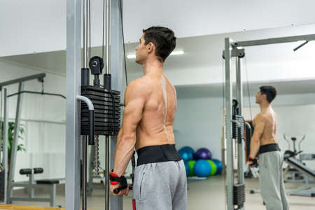 Young man training at sportive equipment in gym
