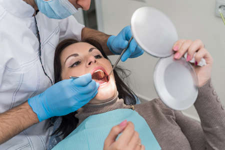 Doctor showing to patient teeth problems in mirror