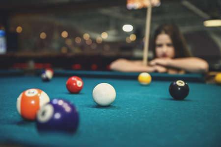 Beautiful woman looking at billiard balls on tableの写真素材