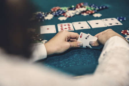 Poker chips and female hands holding playing cards
