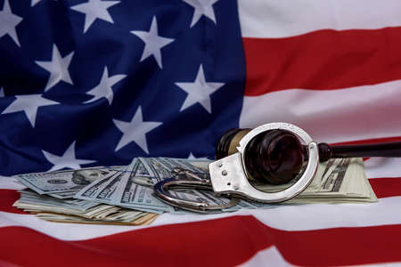 Dollar banknotes with handcuffs and judge's gavel on american flag