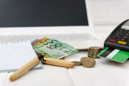Australian dollar with terminal, laptop and notepad