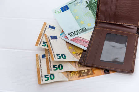 Euro banknotes with brown wallet on table