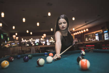 Beautiful woman with long hair playing billiard