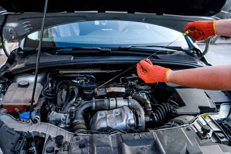 Human hands with oil level meter against car engine