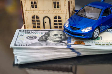 On dollars there is model wooden house and toy car
