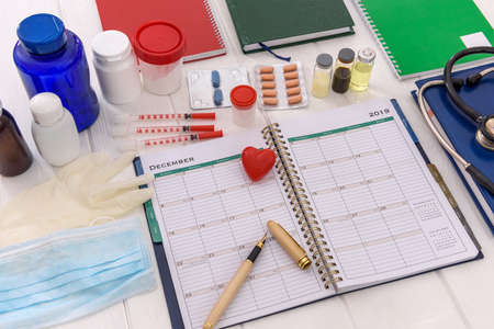 Red heart with pen on diary and pills in bottlesの写真素材