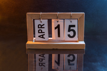 Wooden calendar with date 15th of April on darkの写真素材
