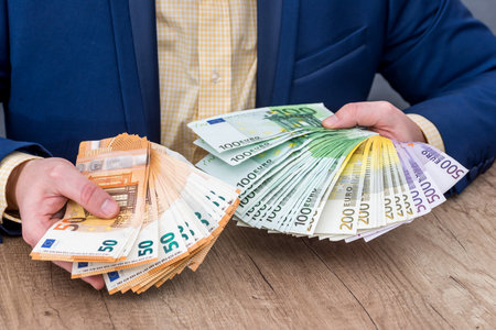 Business person placing euro banknotes into fanの写真素材