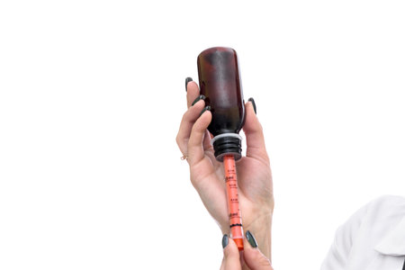 Woman taking medications by syringe from bottleの写真素材