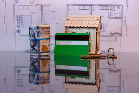 Wooden house model with dollars in roll, credit card and keysの写真素材