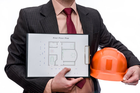 Man in suit with helmet and house plan isolated on white
