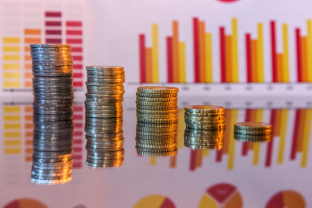 Stake of gold coins with business graphs and reflectionの写真素材