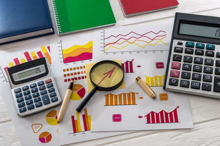 Top view of business graphs with magnifier, pen and calculator