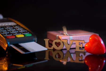 Terminal with credit card and gift box with love text