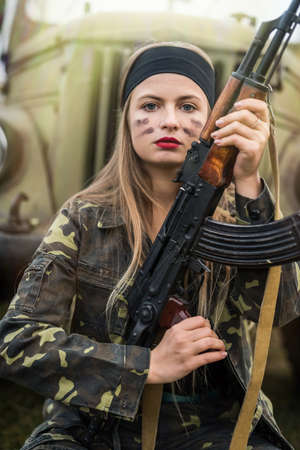 Woman in military uniform with rifle and carの写真素材