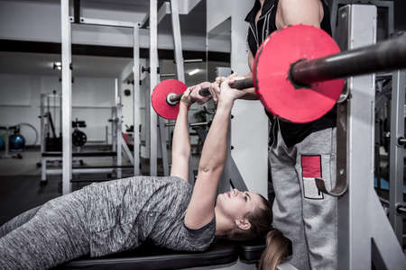 Coach training young and beautiful woman in gym