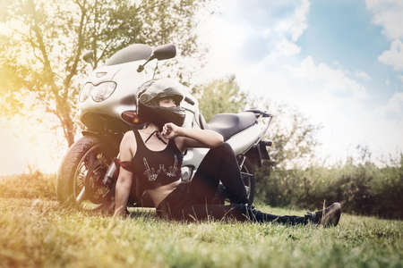 Attractive woman walks on motorbike in summerの写真素材