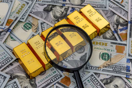 Bullion, gold or ingot on US dollar banknote with magnifierの写真素材