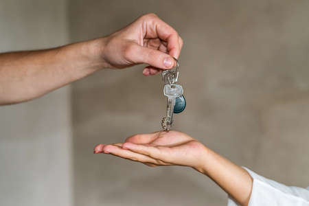 Hands giving and receiving keys from apartment, closeupの写真素材