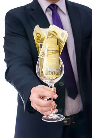Wine glass with euro banknotes in male handsの写真素材