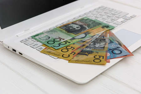 Australian dollar banknotes on white laptop keyboardの写真素材