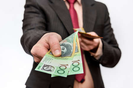 Male hand offering australian dollar banknotes isolated on whiteの写真素材