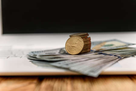 American dollar in coin with paper dollars at laptop keyboardの写真素材