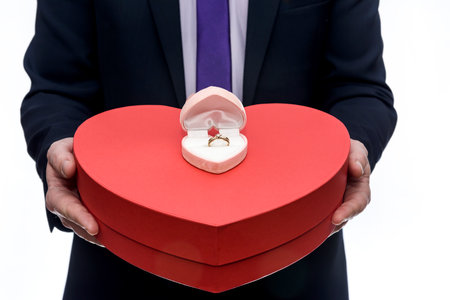 Man offering golden ring and big red heart