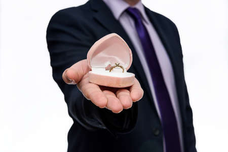 Male hands offering gift box with golden ring inside