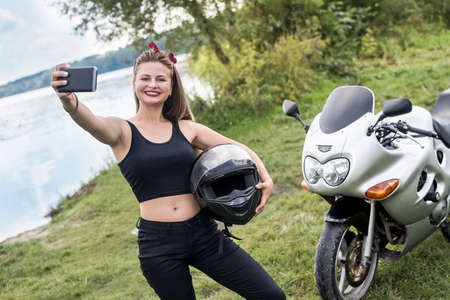 Young woman making selfie on motorbike outdoors