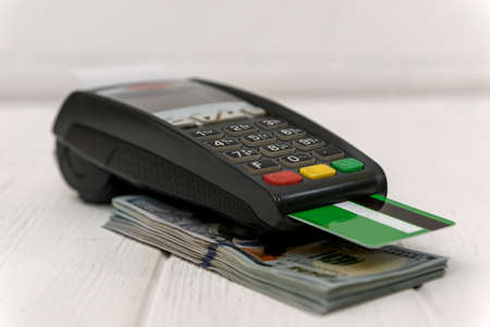 Banking terminal with green credit card and dollar background