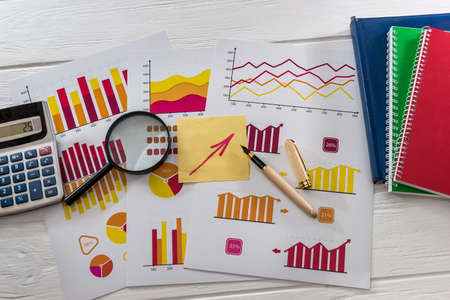 Top view of business graphs with magnifier, pen and calculator