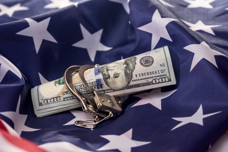 American dollars in handcuffs on national flag