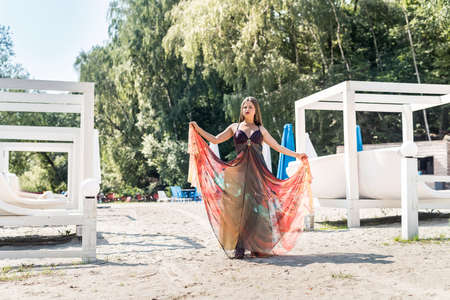 Smiling blonde woman posing in fashion dress on beachの写真素材